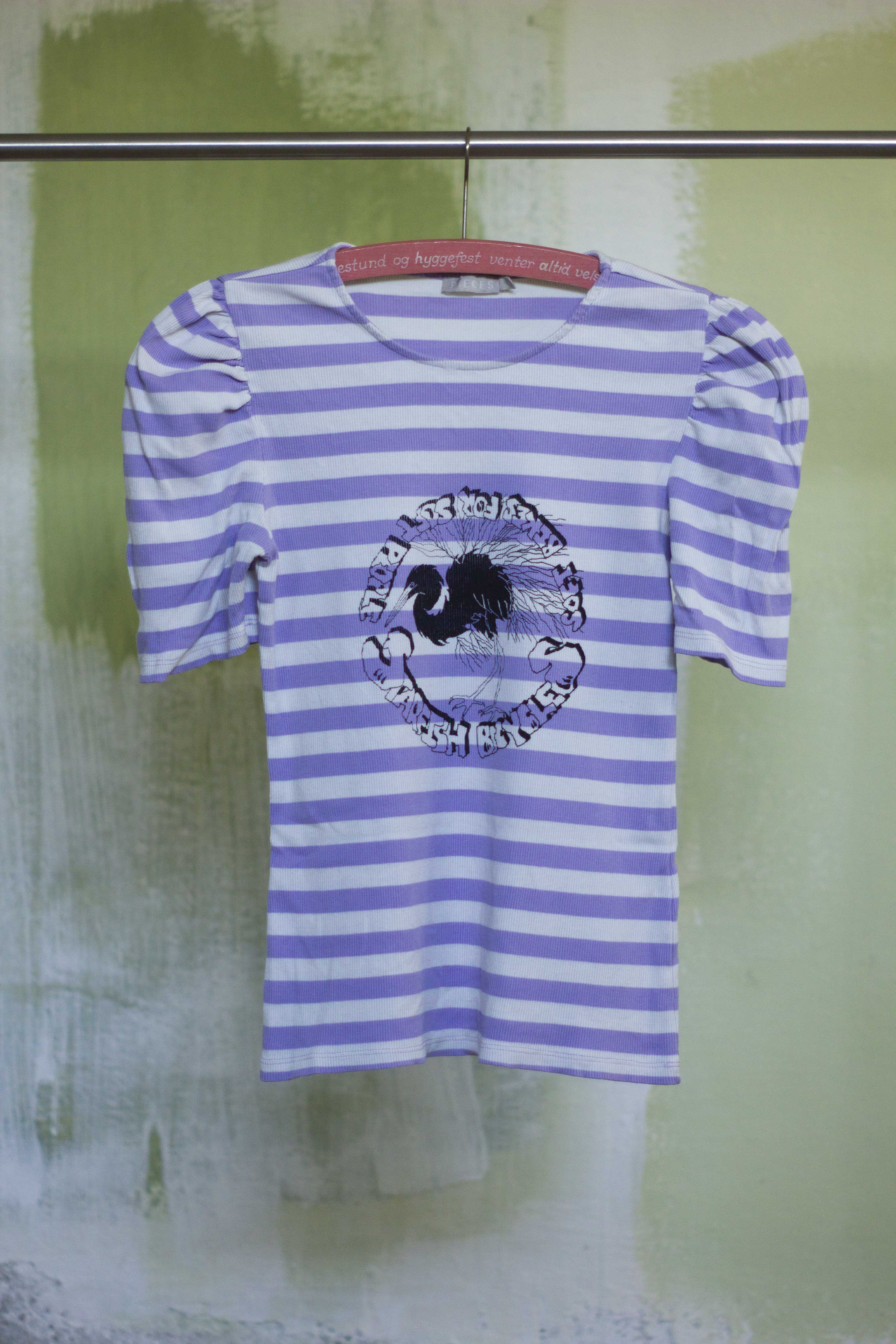 white and purple t shirt with black print of hand drawn silver heron and the text "Starfish Bicycles soft biikes for soft people" in a punkn diy style