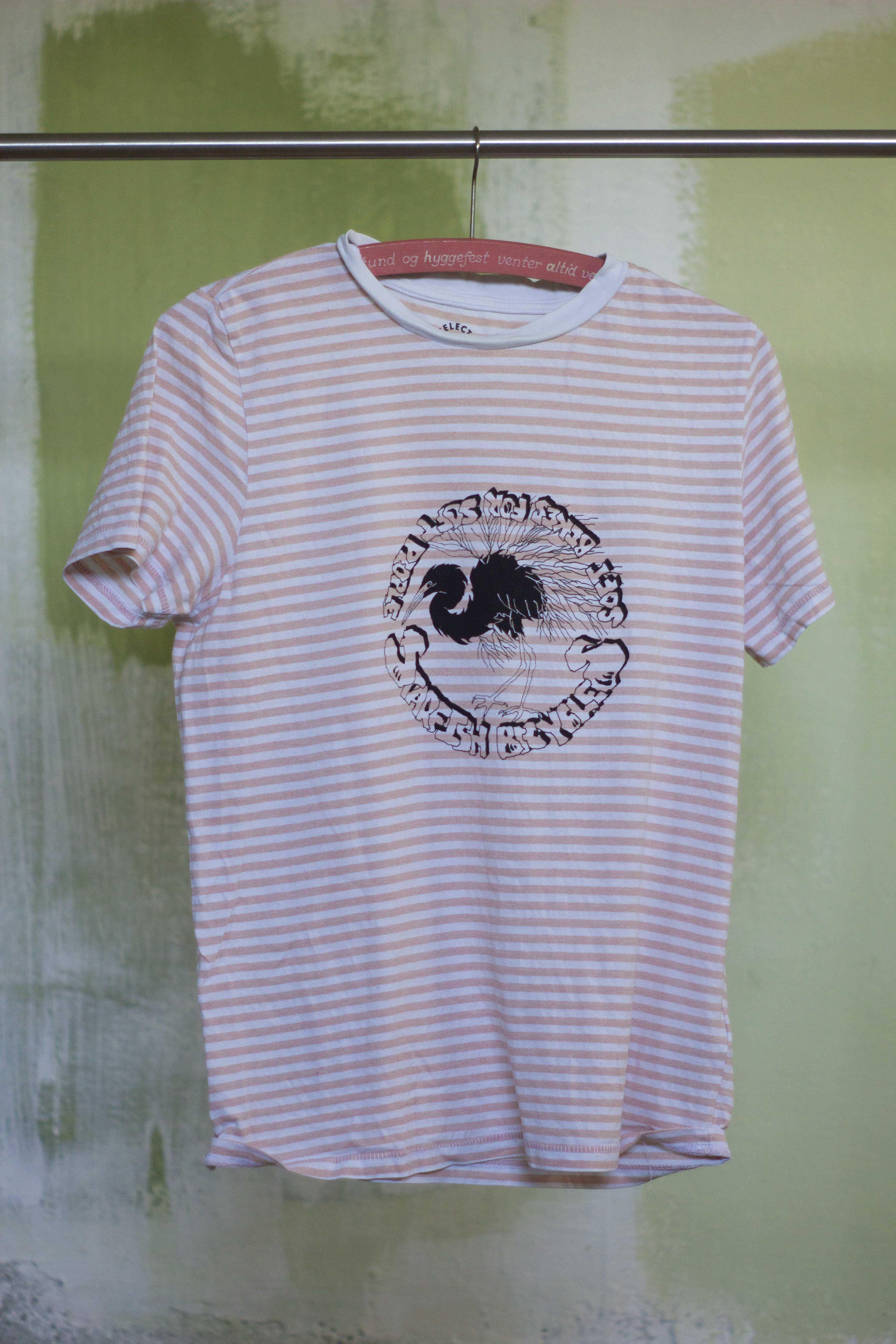 white and salmon t shirt with black print of hand drawn silver heron and the text 