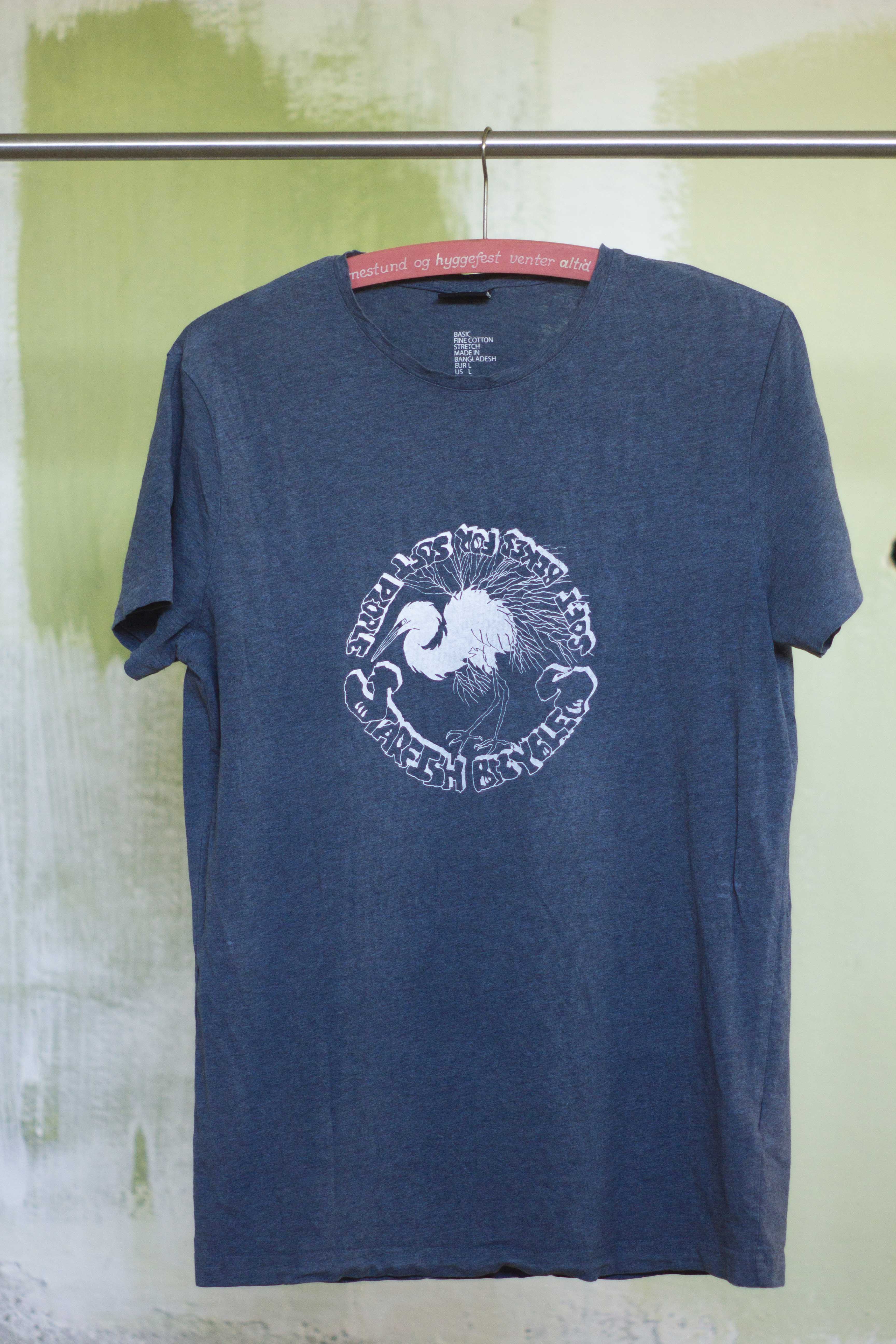 blueish dark grey t shirt with white print of hand drawn silver heron and the text 