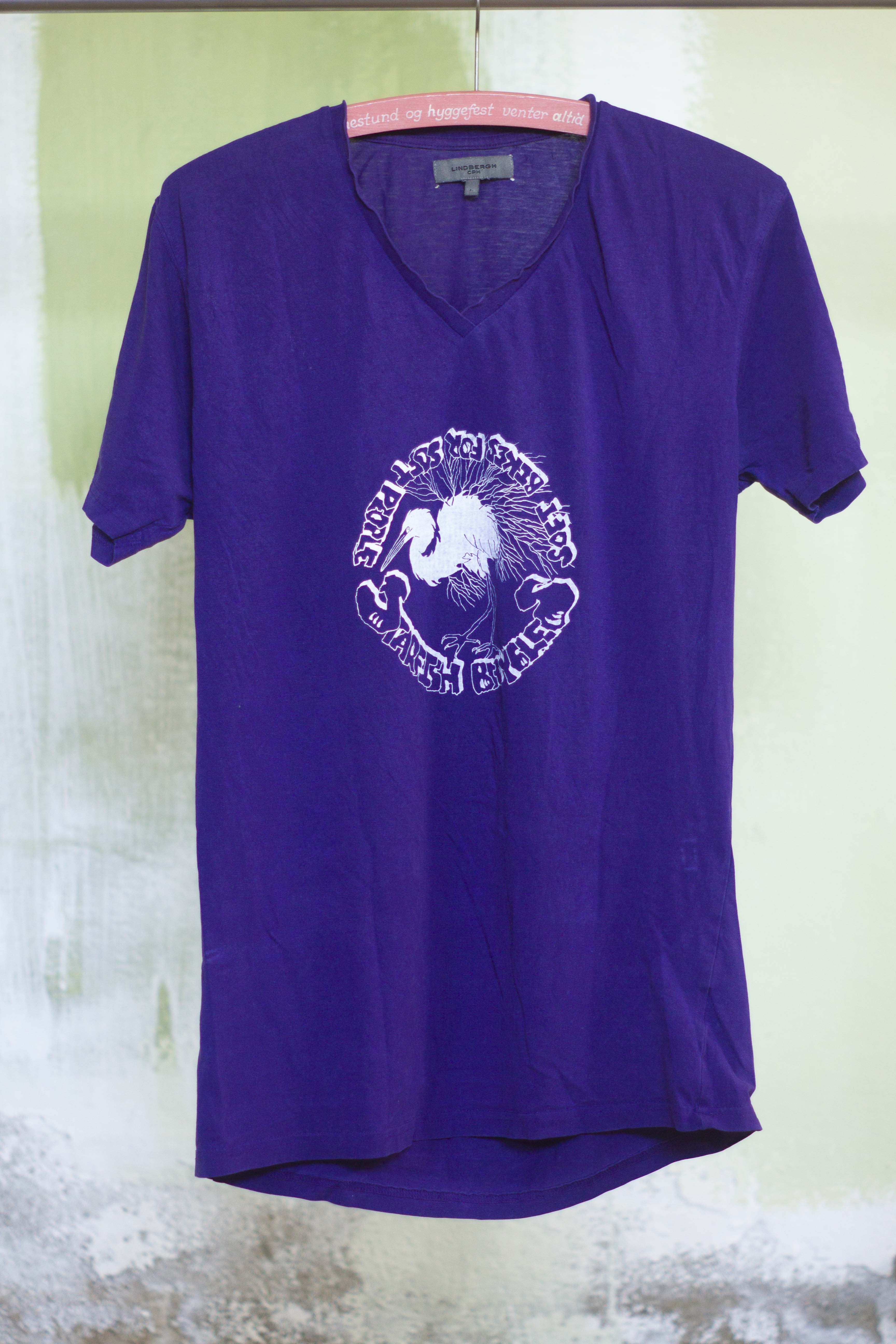 purple t shirt with white print of hand drawn silver heron and the text "Starfish Bicycles soft biikes for soft people" in a punkn diy style