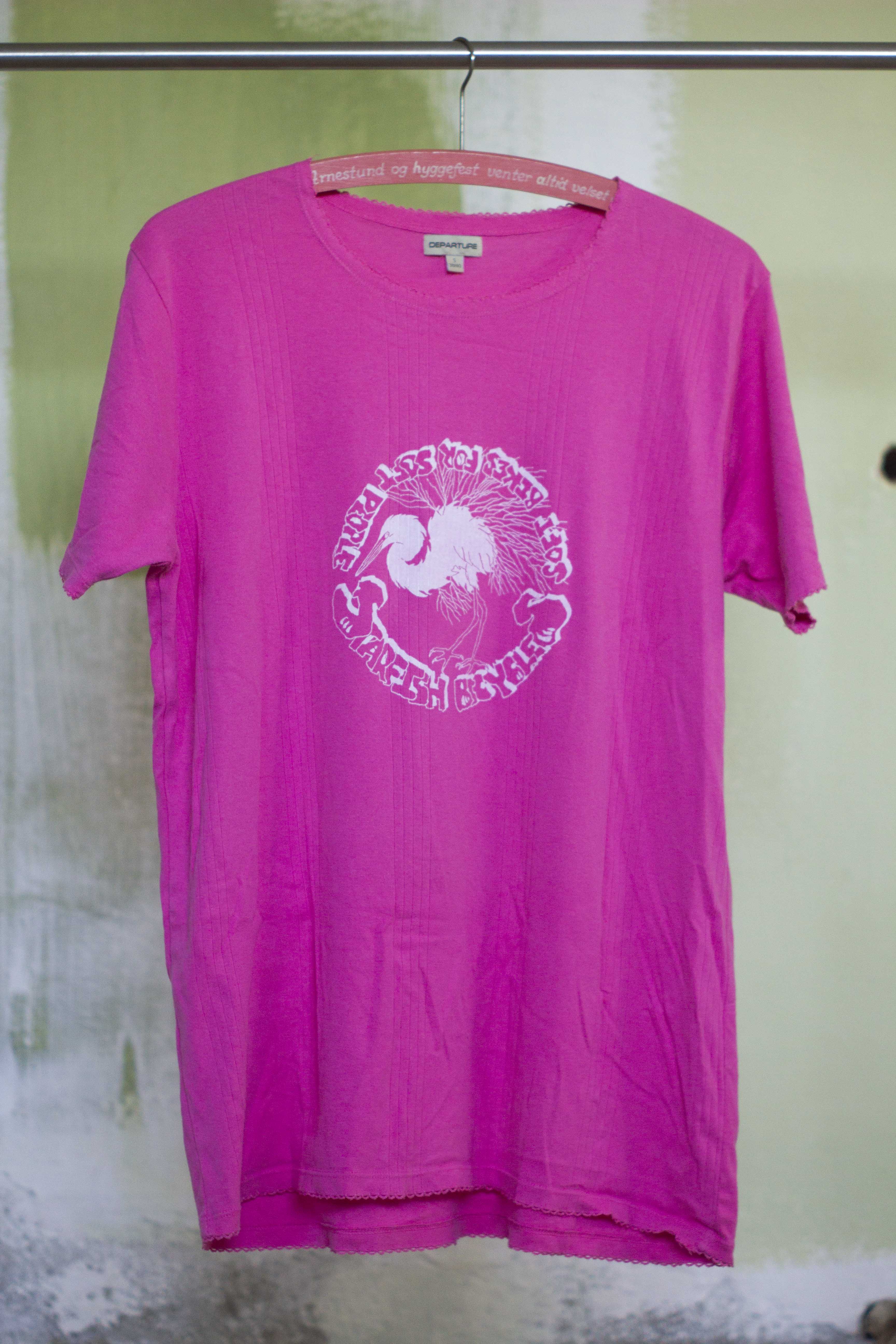 pink t shirt with white print of hand drawn silver heron and the text "Starfish Bicycles soft biikes for soft people" in a punkn diy style